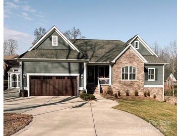 Gray craftsman style home with stone accents, a 3-car garage, and a landscaped yard at 7535 Rabbit Cir, Denver, NC 28037