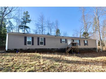 Tan mobile home with brown shutters, deck, and wooded setting at 5122 Wrenn Dr, Denver, NC 28037