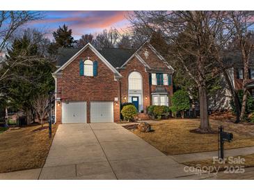 Charming two-story brick home boasts a two-car garage, well-manicured lawn and traditional architectural details at 11911 Farnborough Rd, Huntersville, NC 28078