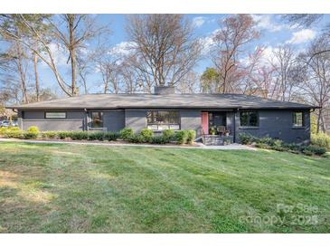 Charming single-story home featuring painted brick, a well-manicured lawn, and a bright pink front door at 4833 Addison Dr, Charlotte, NC 28211