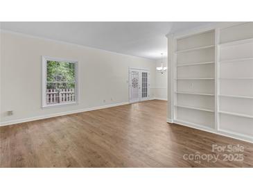 Bright living room with wood floors, large window, built-in shelving, and double glass doors at 5929 Quail Hollow Rd # B, Charlotte, NC 28210