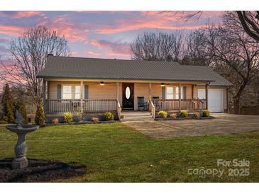 Charming single-story home with inviting front porch, manicured lawn, and water feature at 236 Ervin Rd, Mooresville, NC 28117