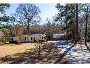 Charming single-story home with mature trees, a long driveway, and fenced storage in a tranquil, wooded setting at 4428 Turkey Ln, Rock Hill, SC 29730