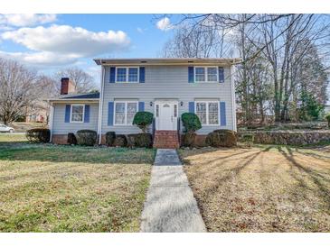 Two-story home featuring blue shutters, brick chimney and entrance, and neatly manicured landscaping at 7707 Ritter Dr, Charlotte, NC 28270