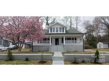 Charming two-story home with covered porch, gray brick foundation, and a beautiful blooming tree in the front yard at 105 N Inman Ave, Bessemer City, NC 28016