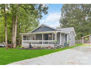 Charming gray home with a welcoming porch and landscaped front yard and gravel driveway at 107 Deese Ct, Indian Trail, NC 28079