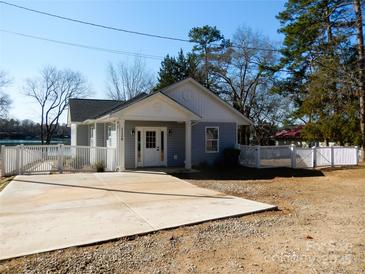 Charming single-story home boasts a white picket fence, a light blue exterior, and a concrete driveway at 1120 Cedar St, Mount Holly, NC 28120