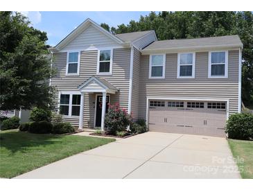Charming two-story home with attached garage, well-maintained lawn, and mature landscaping at 1128 Tangle Ridge Se Dr, Concord, NC 28025