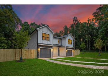 Beautiful home exterior featuring gray siding, stone accents, a well-manicured lawn, and a colorful sunset at 122 I K Beatty St, Charlotte, NC 28214