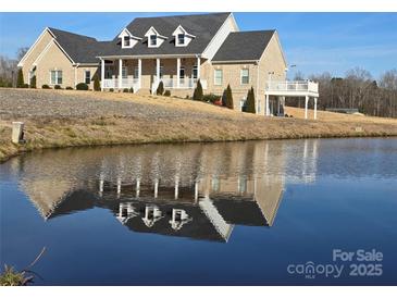 Beautiful brick home featuring a tranquil pond reflecting the house at 2510 Lentz Rd, China Grove, NC 28023