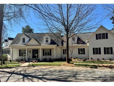 Charming white home with black shutters, a covered porch, and manicured landscaping at 357 Magnolia St, Davidson, NC 28036