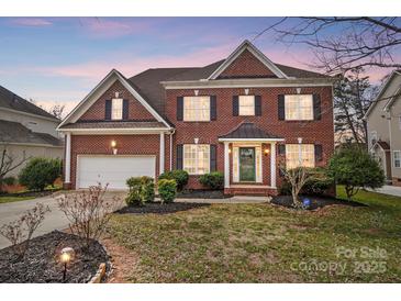 Charming two-story brick home featuring a well-manicured lawn, attached garage and traditional architectural details at 561 Ambergate Nw Pl, Concord, NC 28027