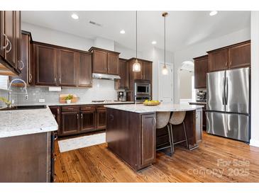 Modern kitchen features dark wood cabinetry, stainless steel appliances, and a spacious island with bar seating at 6361 Willow Farm Dr, Denver, NC 28037