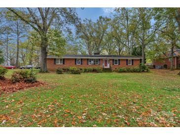 Charming single-story brick home featuring a well-maintained lawn and beautiful mature trees at 725 Plantation Rd, Lancaster, SC 29720