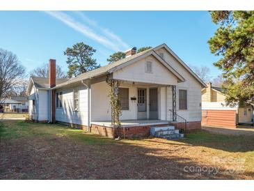 Charming, white, single-story home with front porch, brick accents, mature trees and well-maintained lawn at 105 W 21St St, Kannapolis, NC 28081