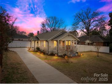 Charming home with a welcoming front porch, long driveway, and beautiful, colorful sunset at 27 Dove Sw Ave, Concord, NC 28025