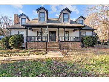 Two-story white brick home with black accents, a front porch, and landscaping at 8478 Rocky River Rd, Harrisburg, NC 28075