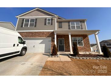 Charming two-story home featuring stone accents, gray siding, and a two-car garage at 104 Sycamore Crossing Ct, Locust, NC 28097