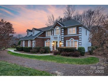 Charming brick home featuring well-manicured landscaping and a welcoming entrance with a small balcony above at 10417 Sutherby Dr, Charlotte, NC 28277