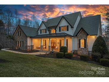 Charming home with a stone and siding exterior, covered front porch, manicured lawn, and professionally landscaped yard at 134 Wild Harbor Rd, Mooresville, NC 28117