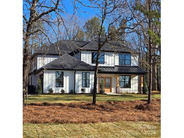 Beautiful two-story home featuring a modern white facade with black accents, wood-look door and a manicured front yard at 4605 Western Union School Rd, Waxhaw, NC 28173