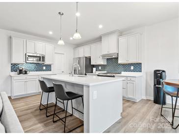 Modern kitchen features a central island, white cabinetry, stainless appliances, and stylish backsplash at 1036 Barnette Farm Ln, Monroe, NC 28110