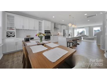 Bright kitchen features stainless steel appliances, white cabinetry and an island with bar seating at 14139 Loyola Ridge Dr, Charlotte, NC 28277