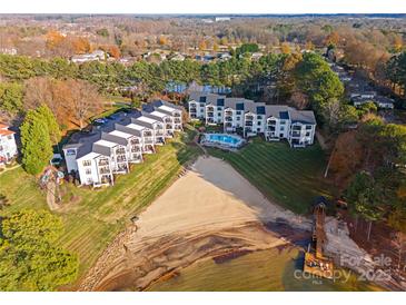 Aerial view of lakeside condos with beach access and a refreshing swimming pool, surrounded by lush landscaping at 17811 Half Moon Ln # E, Cornelius, NC 28031