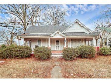 Charming white house with wrap-around porch and mature landscaping at 830 Lowder St, Albemarle, NC 28001