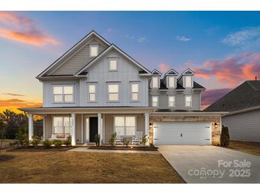 Inviting two-story home featuring a welcoming front porch with a swing and a two-car garage at 5024 Hillshire Ln, Mint Hill, NC 28227