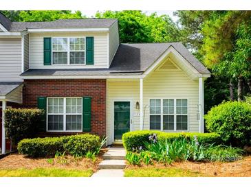 Charming townhome with a mix of brick and siding, complemented by lush landscaping and vibrant green shutters at 1748 Pergola Pl, Charlotte, NC 28213