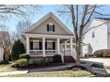 Charming home with a welcoming front porch, complemented by manicured landscaping and mature trees under a bright blue sky at 319 Ohenry Ave, Davidson, NC 28036