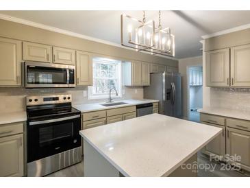 Updated kitchen with island, stainless steel appliances, and light cabinets at 833 E Chestnut St, Stanley, NC 28164