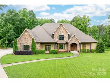 Charming stone-accented home featuring a meticulously manicured lawn and mature landscaping at 148 Castle Dr, Mooresville, NC 28117