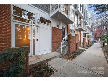 Townhouse exterior featuring a brick and gray wood facade, small balconies, and front door at 287 Mcdonald Ave, Charlotte, NC 28203