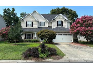 Charming two-story home featuring a well-manicured lawn, flowering trees, and a welcoming front porch at 5934 Hickory Hollow Ct, Harrisburg, NC 28075
