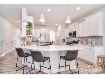 A spacious kitchen features an island with bar seating, white cabinets, and modern lighting fixtures at 124 Doncaster Dr, Mooresville, NC 28115