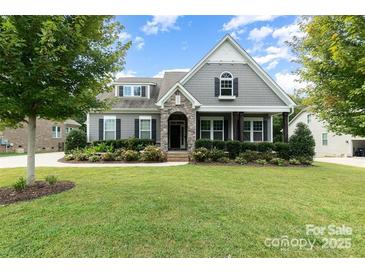 Gray two-story house with stone accents, landscaped yard, and a three-car garage at 1320 Torrens Dr, Wesley Chapel, NC 28110