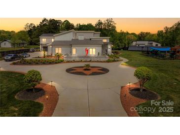 Stunning home with circular driveway, lush landscaping, and modern design creating a grand and inviting curb appeal at 15700 Youngblood Rd, Charlotte, NC 28278