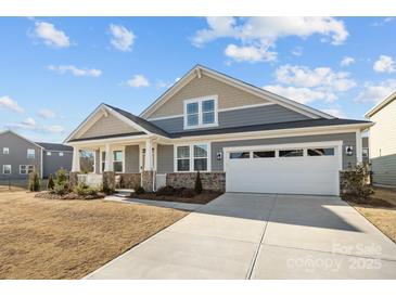 Charming home features a two-car garage, covered porch, and stylish stone and siding accents at 1503 Ainslie Place Rd, Indian Trail, NC 28079