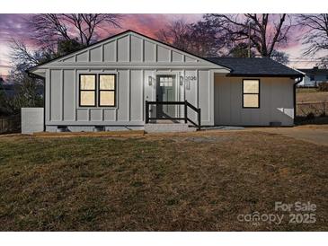 Newly renovated farmhouse style home with a gray door and modern landscaping at 3020 Bellaire Dr, Charlotte, NC 28216