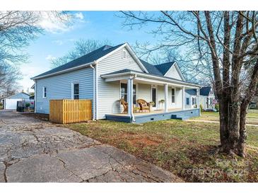 Charming home featuring a welcoming front porch with rocking chairs and mature trees at 909 1St S Ave, Conover, NC 28613