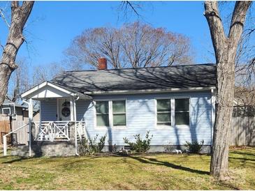 Charming light blue home featuring a welcoming front porch, well-maintained lawn and a beautiful treed front yard at 128 N Oak St, Salisbury, NC 28146