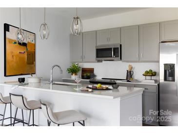 Bright kitchen features modern appliances, quartz countertops, gray cabinets, and stylish pendant lighting at 4114 Lattistep Ln, Charlotte, NC 28269