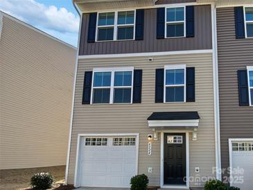 Two-story townhome with beige siding, a white garage door, and a black front door at 6324 Cutwater Cir, Charlotte, NC 28269