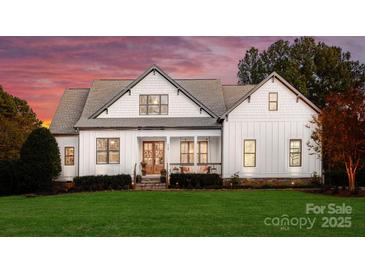 Stunning exterior view of a modern farmhouse with beautiful white siding, gray roof, and a lush green lawn at 117 Yellow Jacket Cir, Mooresville, NC 28117