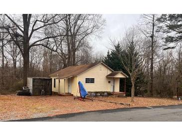 Modest single-story home with vinyl siding and a simple gable roof, surrounded by mature trees and a leafy yard at 1349 14Th Ne Ave, Hickory, NC 28601