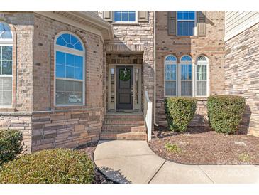 Inviting front entrance with stone facade, arched windows, and a decorative wreath on the dark-colored door at 9116 Arnsberg Dr, Waxhaw, NC 28173