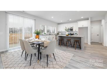Bright, open kitchen and dining area featuring white cabinets, stainless appliances, and light gray plank floors at 120 Random Dr, Salisbury, NC 28147