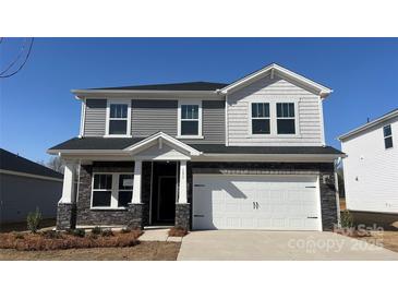 Two-story home featuring stone accents, a white garage door, and a well-manicured lawn on a sunny day at 151 Aberdeen Dr, Salisbury, NC 28144